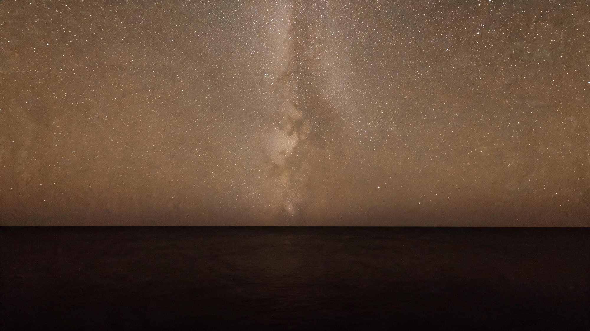 The southern night sky low over a black ocean horizon