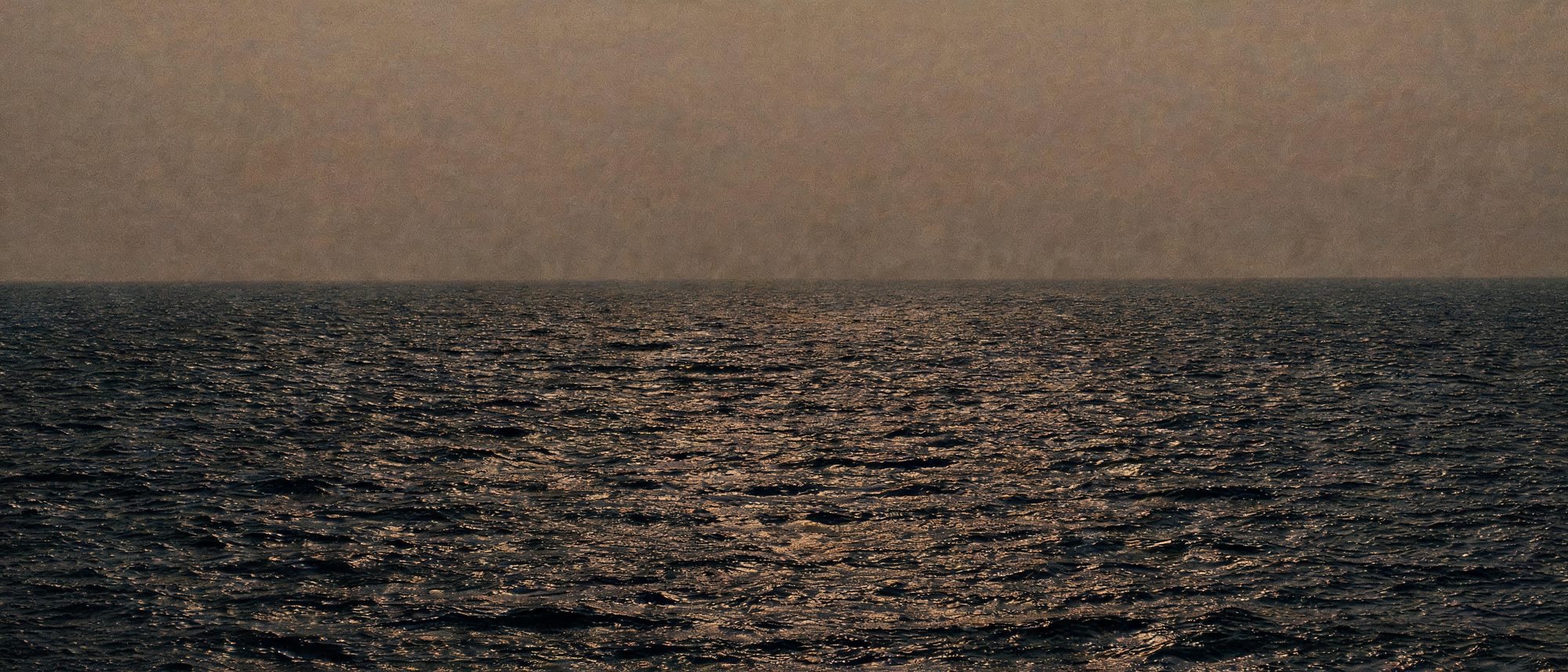 Wind moving across dark open ocean at last light